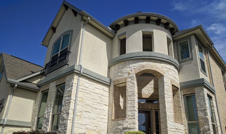 A two story beige stone brick home sparkling and spotless after receiving window cleaning services