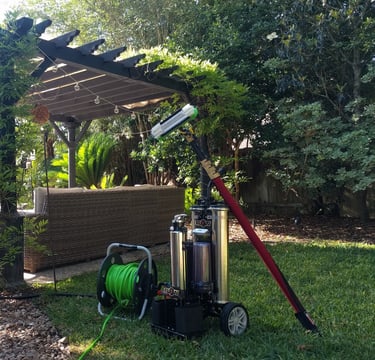 Window cleaning equipment and water filtration system setup in a backyard next to a gazebo and pool