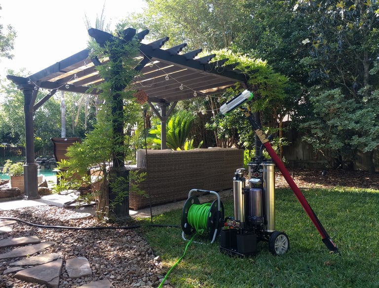 Window cleaning equipment and water filtration system setup in a backyard next to a gazebo and pool