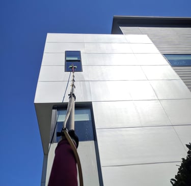 Cleaning a window on a second story commercial building with a five stage filtration water pool