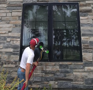 A man cleaning windows for a luxury home with a five stage filtration water pool